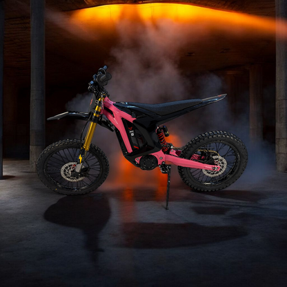 A bold hot pink and black electric dirt bike featuring gold forks and a red rear spring with smoky effect on the background. 
